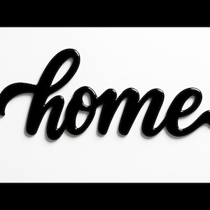 May include: A black cursive "home" sign against a white background. The word is in a flowing script, with a glossy finish, and casts a subtle shadow. The sign is a decorative element for home decor.