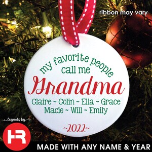 May include: A white ceramic Christmas ornament with a red ribbon. The ornament reads "my favorite people call me Grandma" in green and red script, with names and the year 2022.
