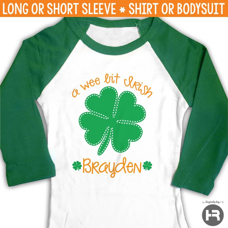 Pu&ograve; includere: Una maglietta o un body bianco a maniche lunghe o corte con maniche raglan verdi. La maglietta presenta un trifoglio a quattro foglie verde con cuciture bianche e il testo "a wee bit Irish" in arancione. Il nome "Brayden" &egrave; scritto in arancione sotto il trifoglio.