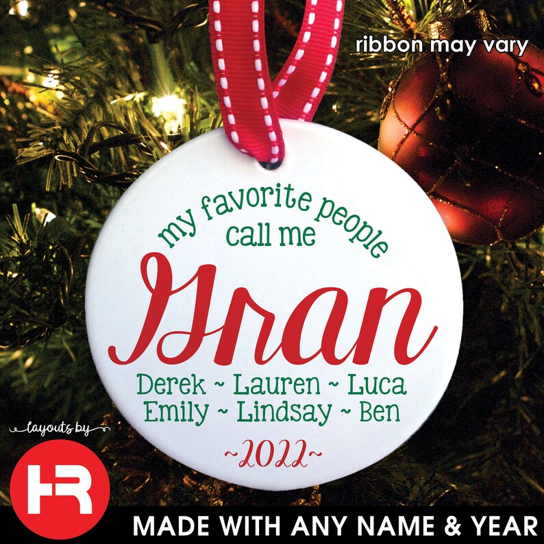 May include: White ceramic Christmas ornament with red and green text. The ornament reads "my favorite people call me Gran" with a list of names and the year "2022". A red ribbon is attached for hanging.
