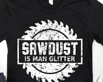 Könnte beinhalten: Schwarzes T-Shirt mit einem weißen Sägeblatt-Motiv und dem Text "Sawdust is Man Glitter".