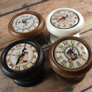 May include: Four wooden knobs with different clock faces. The knobs are painted in white, black, and brown. The clock faces feature various designs, including a bird, a fish, and a horse.