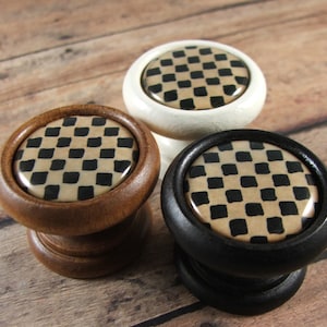 May include: Three wooden knobs with black and tan checkered patterns. The knobs are in white, brown, and black.