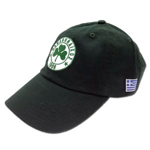 May include: A black baseball cap with a green clover logo and the text "PANATHINAIKOS 1908". The cap also has a small Greek flag patch on the side.
