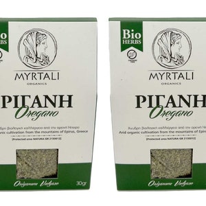 May include: Two white boxes with green accents, each containing 30 grams of dried oregano. The boxes feature the brand name "MYRTALI ORGANICS" and the product name "ΡΙΓΑΝΗ Oregano". The text on the boxes reads "Arid organic cultivation from the mountains of Epirus, Greece. Protected area NATURA GR 2130012."
