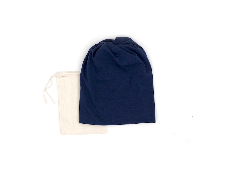 Pu&ograve; includere: Un berretto di stoffa blu navy con un nodo sulla cima, confezionato in una borsa di stoffa bianca con coulisse.