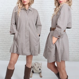 May include: A brown and white plaid dress with a collared neckline and long sleeves. The dress has a fitted bodice and a flared skirt. The dress is worn by a person with brown hair and brown boots.