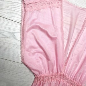 May include: A pink sheer dress with a V-neckline and lace trim. The dress has a gathered waist and a flowing skirt.