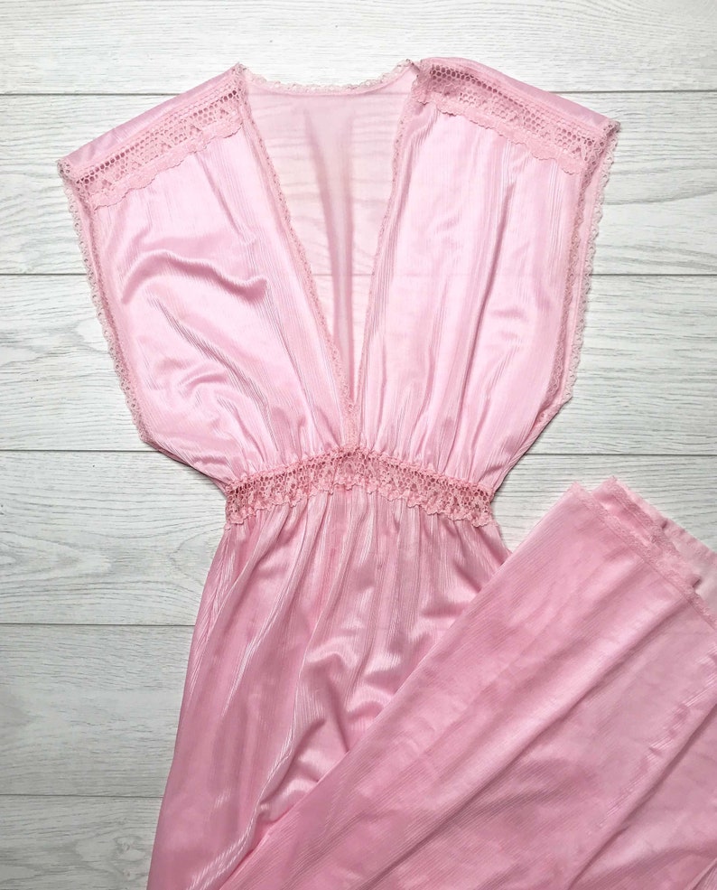 May include: A pink sleeveless maxi dress with a lace trim around the neckline and a gathered waist.