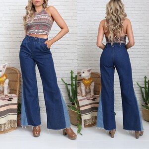 Pode incluir: Uma mulher vestindo uma cal&ccedil;a jeans azul de perna larga com um painel de jeans azul claro nas laterais. A cal&ccedil;a tem cintura alta e perna flare. A mulher tamb&eacute;m est&aacute; vestindo um top halter estampado.