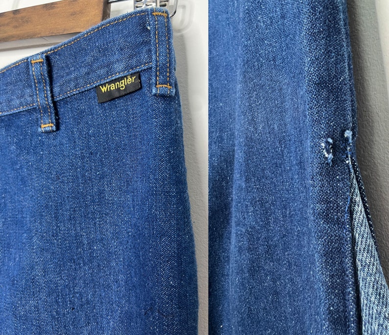 Pode incluir: Um par de cal&ccedil;as de ganga azuis com uma costura dividida na perna direita. As cal&ccedil;as de ganga t&ecirc;m uma etiqueta Wrangler no bolso de tr&aacute;s.