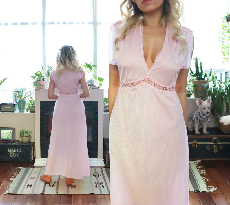 May include: A long, pink, sleeveless nightgown with a lace trim around the neckline and waist. The gown is made of a soft, silky fabric.