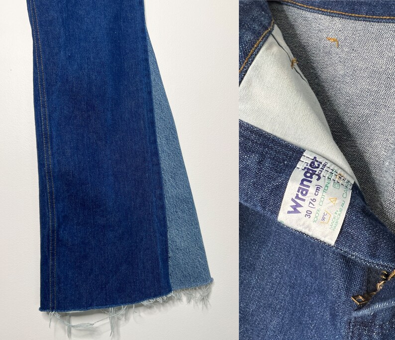 Pode incluir: Um par de cal&ccedil;as de ganga azuis de boca de sino com bainha desfiada. As cal&ccedil;as de ganga t&ecirc;m um painel de ganga azul contrastante na parte de tr&aacute;s de cada perna. As cal&ccedil;as de ganga t&ecirc;m uma etiqueta Wrangler com o texto "Wrangler 30/76 cm 100% algod&atilde;o" no bolso direito de tr&aacute;s.