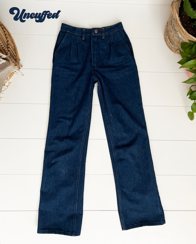 K&ouml;nnte beinhalten: Eine dunkelblaue, hochgeschnittene, weite Jeans mit Knopfleiste und Falten vorne.