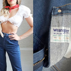 May include: A pair of blue denim jeans with a white Wrangler label that reads "30 (76 cm)" and "100% Cotton".