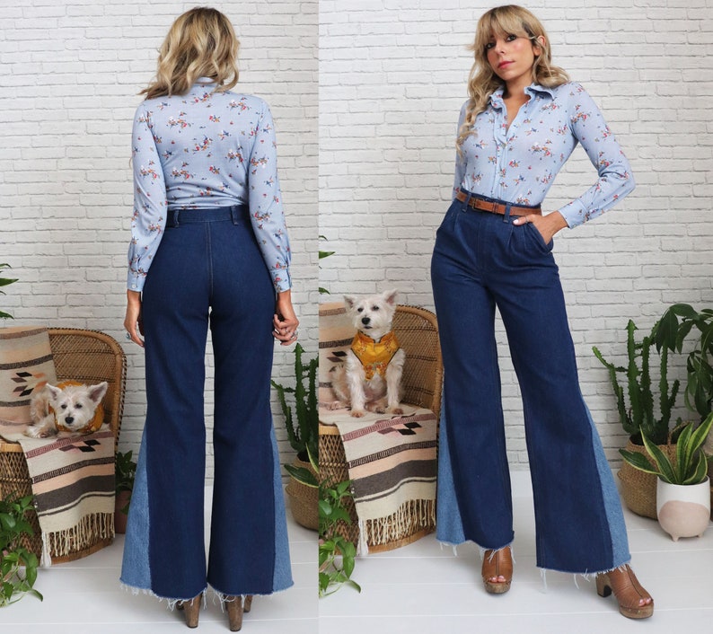 Pode incluir: Duas mulheres vestindo camisas de estampa floral azul e branca e cal&ccedil;as boca de sino de jeans azul com um painel azul contrastante nas laterais. Ambas as mulheres est&atilde;o usando cintos marrons. Uma das mulheres est&aacute; de p&eacute; com as m&atilde;os nos quadris, a outra est&aacute; de p&eacute; com as m&atilde;os nos bolsos. Ambas as mulheres est&atilde;o sorrindo.