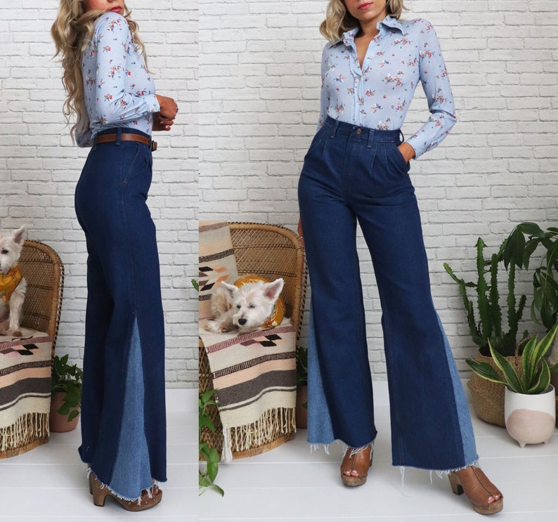 Pode incluir: Uma mulher est&aacute; vestindo uma blusa azul claro com estampa floral e uma cal&ccedil;a de sino azul jeans com um painel de jeans contrastante na lateral. Ela est&aacute; em p&eacute; na frente de uma parede de tijolo branco.