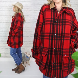 May include: A red and black plaid flannel jacket with a corduroy collar and two large pockets. The jacket is unbuttoned and has a zipper closure.
