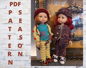 May include: Two dolls dressed in handmade knitted outfits. One doll wears a teal sweater, yellow jacket and pants, and a burgundy hat. The other doll is in a matching knitted ensemble of a jacket, pants, and hat in shades of navy, orange, and brown.
