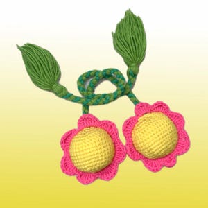 Puede incluir: Adornos de flores de ganchillo. Las flores tienen pétalos rosas, centros amarillos y hojas verdes. Las flores están conectadas por un tallo trenzado verde y amarillo. El fondo es un degradado de amarillo.