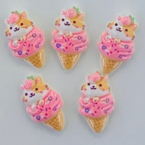 May include: Five adorable cat ice cream cone charms with pink and white frosting, sprinkles, and a strawberry on top. The cats are wearing a pink and white sweater.