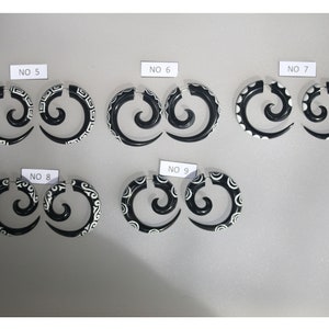 Peut inclure: Ensemble de six paires de boucles d'oreilles en forme de spirale noires et blanches avec différents motifs. Les boucles d'oreilles sont numérotées de 5 à 9.