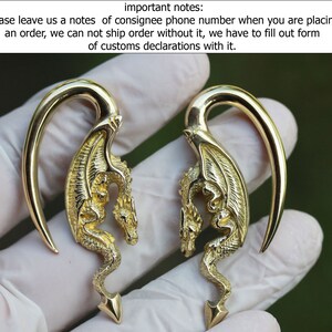Puede incluir: Un par de expansores de oreja en forma de dragón de color dorado. Los expansores están hechos de metal y tienen una forma curva. Los dragones están detallados con alas y escamas.