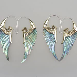 Puede incluir: Un par de pendientes de oro y nácar de abulón iridiscente con forma de alas de ángel. Los pendientes son de estilo colgante y tienen un diseño de aro.