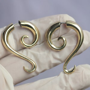 May include: A pair of gold spiral ear gauges. The gauges are made of metal and have a smooth, polished finish.