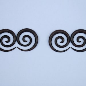 May include: A pair of dark brown wooden double spiral ear gauges. The gauges are made of wood and have a double spiral design.