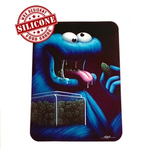 May include: A blue, furry monster with big eyes and a wide open mouth is holding a green bud in its right hand. The monster is drooling and has a pink tongue sticking out. The monster is standing in front of a clear container filled with green buds. The container is labeled "Food Grade Silicone Wax Resistant".