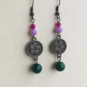 May include: A pair of dangle earrings with a flower charm, green, purple, and pink beads.