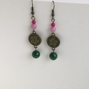 Może przedstawiać: Para kolczyków wiszących z różowymi i zielonymi koralikami i brązowym wisiorkiem w kształcie kwiatu.
