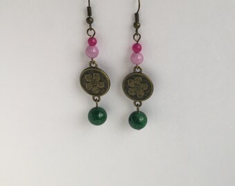 May include: A pair of dangle earrings with pink and green beads and a bronze flower charm.