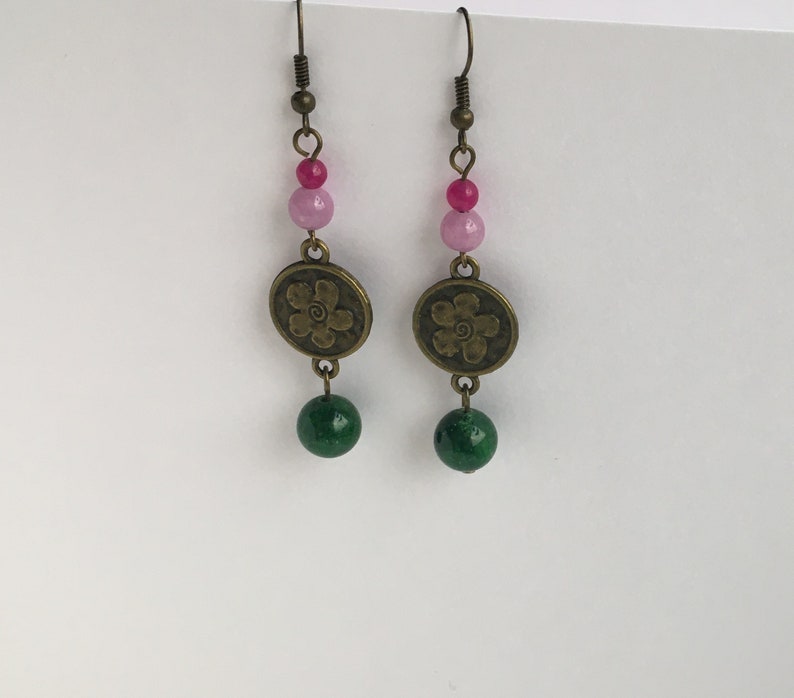 May include: A pair of dangle earrings with pink and green beads and a bronze flower charm.