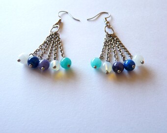 May include: A pair of silver dangle earrings with multiple chains and colorful gemstone beads. The beads are white, blue, purple, and turquoise.