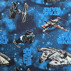 May include: Fabric with a Star Wars theme. The design features various spacecraft, including TIE fighters, X-wings, and the Millennium Falcon, set against a blue space background with the words "STAR WARS" in blue.