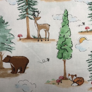 May include: A white fabric with a woodland pattern featuring a brown bear, a deer, a fox, and several green trees. The background is white with brown and green accents.