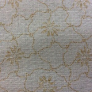 May include: A white fabric with a delicate pattern of small brown flowers. The fabric has a subtle texture and a slightly off-white color.