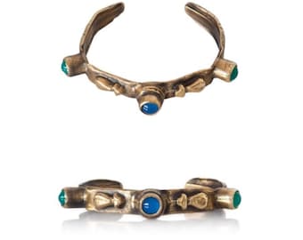 May include: A gold-toned bracelet with green and blue gemstones. The bracelet is open and has a simple design.