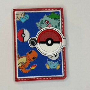 May include: A blue wallet with red trim and white stitching, featuring embroidered images of Pokémon characters and a Poké Ball closure. The wallet includes images of Bulbasaur, Charmander, and Piplup.