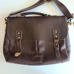 May include: A brown leather messenger bag with a flap closure, two adjustable straps, and brass hardware.