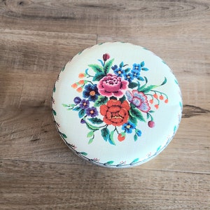 Vintage round tin chocolates box with embroidery flowers design. Floral metal cookie box.