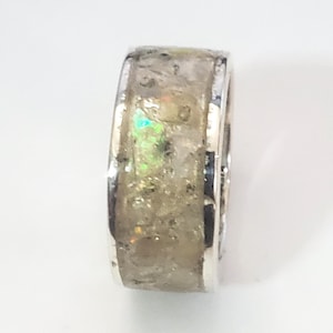May include: A silver ring with a white and iridescent inlay. The inlay has a speckled appearance.