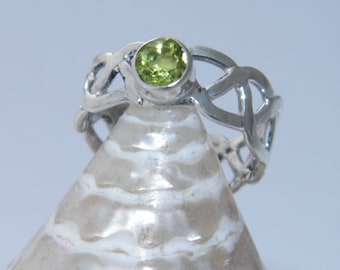 May include: A silver Celtic knot ring with a green peridot gemstone.