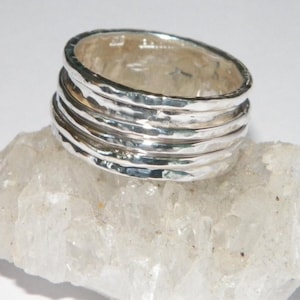 May include: A silver ring made of five stacked bands, each with a hammered texture.