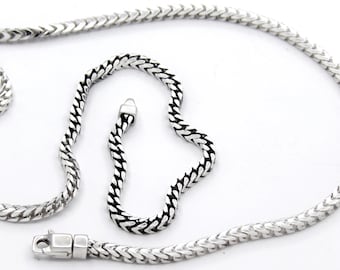 May include: Two silver chains, one longer than the other, with a box clasp. The chains are made of a braided design.