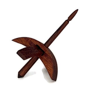 May include: A wooden spinning wheel with a dark brown finish. The wheel is shaped like a crescent moon and has a spindle that extends out from the center.