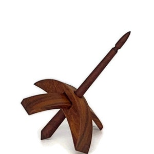 May include: A wooden drop spindle for hand spinning yarn. The spindle is made of dark brown wood. It has a central shaft with a pointed tip and a cross-shaped whorl at the base. The design is simple and functional, a traditional craft tool.