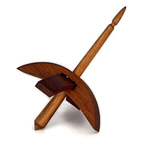 May include: A wooden drop spindle with a dark brown whorl and a long, tapered shaft. The spindle is made of light brown wood and is designed for spinning yarn. The image is set against a white background.